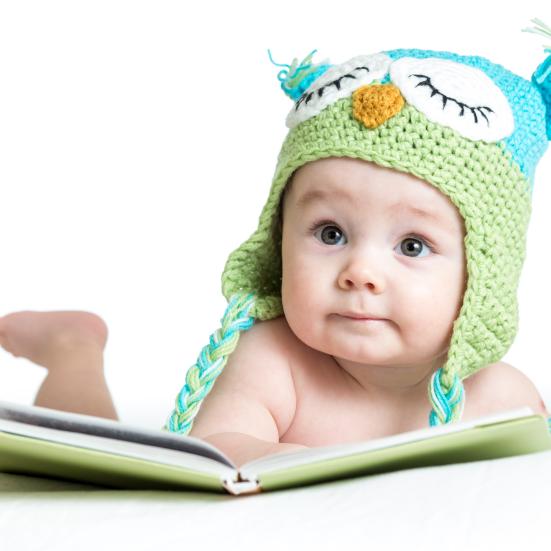Baby med hue kigger i en billedbog.